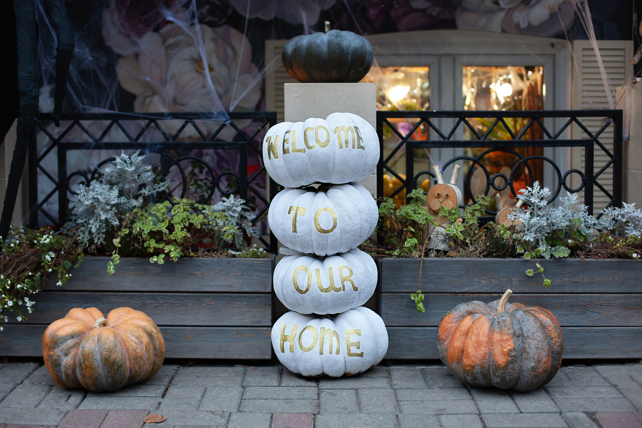 hand painted white pumpkins for fall decorating stacked on top of each other with a welcome message