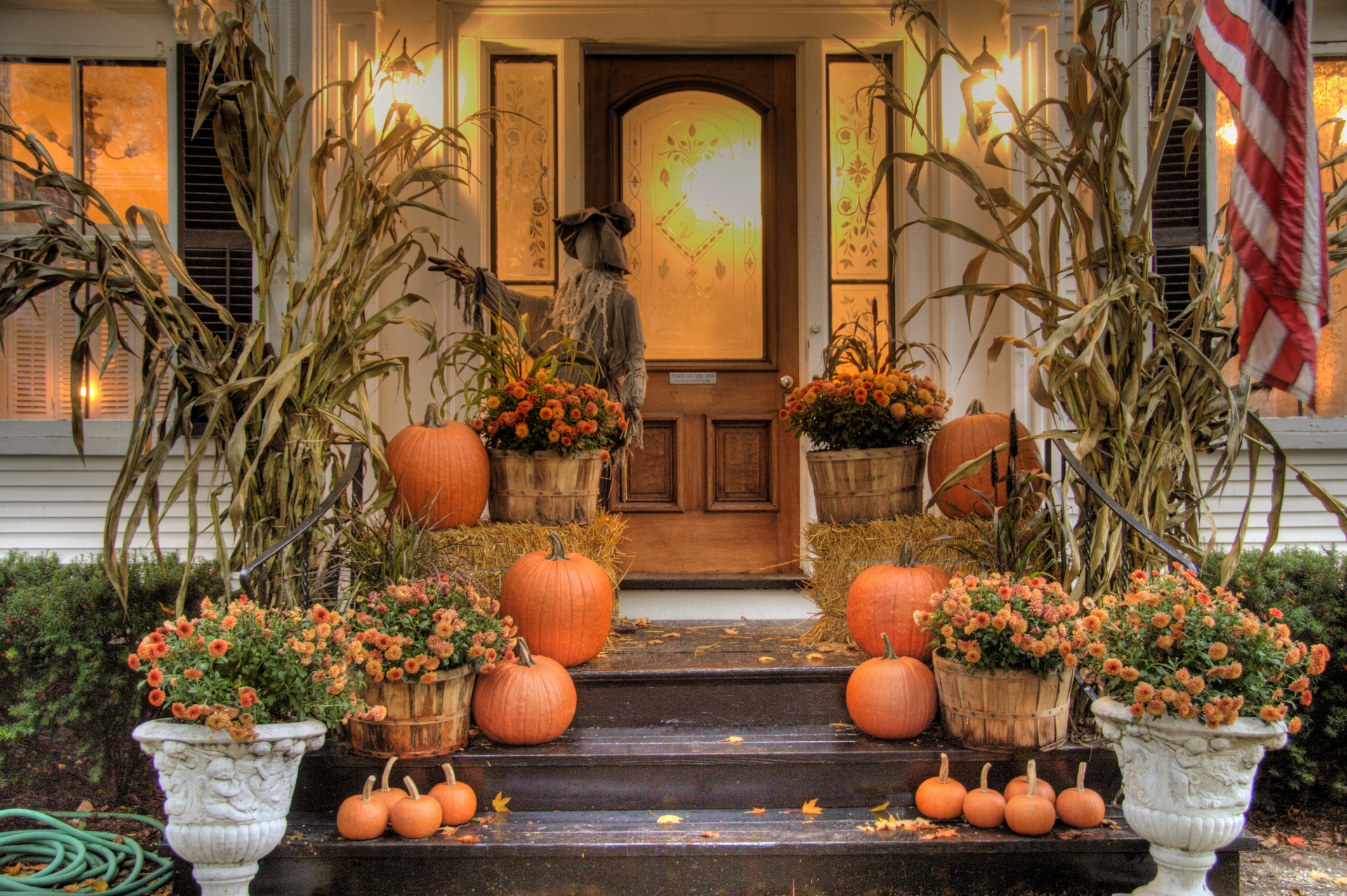 fall front porch with hay bales, scarecrow and corn stalks